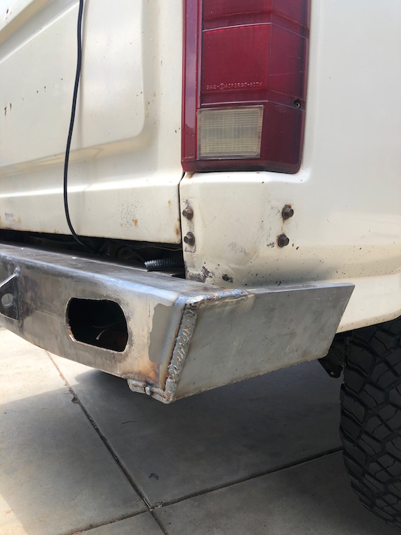 White 1981 Ford Bronco rear bumper and taillight assembly with custom metal bumper.