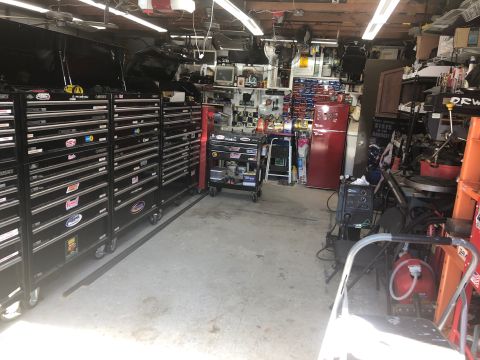 1992 Jeep Wrangler - This is a cluttered garage scene with many toolboxes, a red refrigerator, and various equipment. There are no vehicles visible in the image.