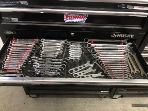1992 Jeep Wrangler - A close-up view of a mechanic's tool chest drawer filled with various wrenches. The tools are neatly organized on red and black holders, wi…