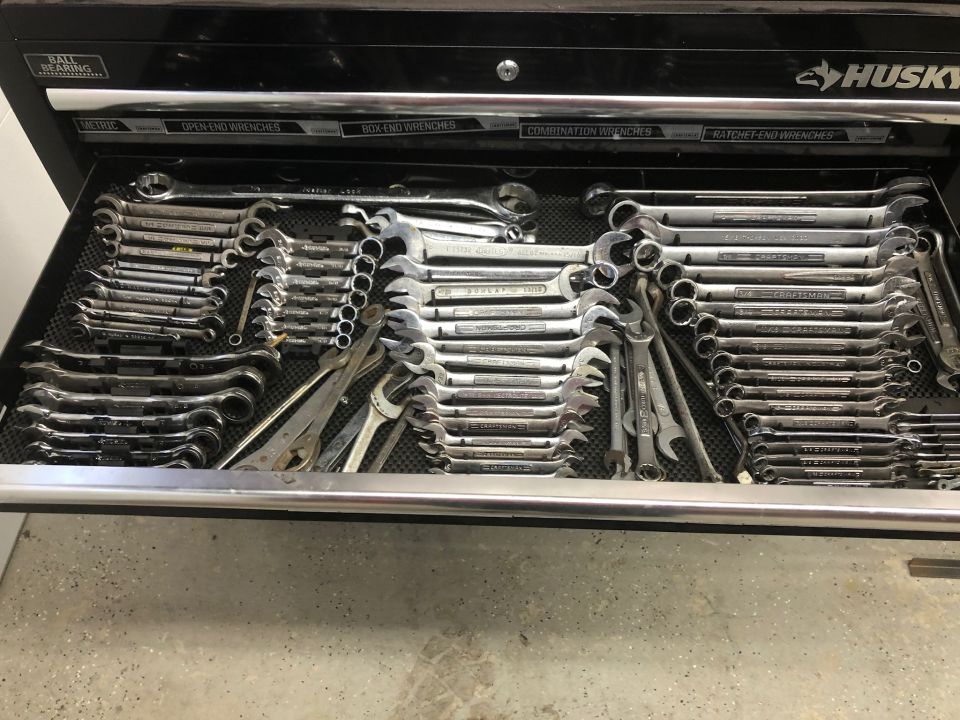 Open toolbox drawer filled with wrenches and pliers.