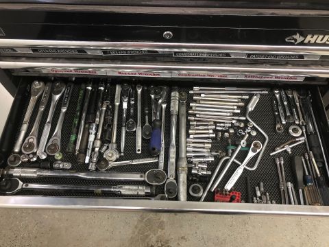 1992 Jeep Wrangler - An open drawer of a black tool chest filled with various wrenches, ratchets, and sockets. The tools are neatly organized on a black texture…