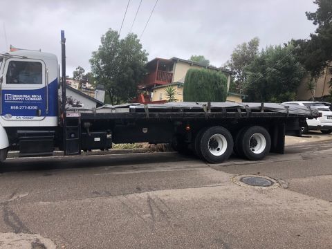 1992 Jeep Wrangler - A flatbed truck with "INDUSTRIAL METAL SUPPLY COMPANY" text on the side is parked on a residential street. The truck has a black flatbed lo…