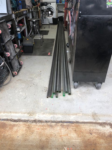 1992 Jeep Wrangler - A collection of metal pipes are laid out on a concrete floor in a garage. The pipes have green caps on some of their ends.