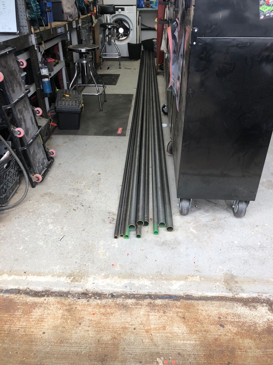 Metal pipes with green caps on a concrete garage floor.