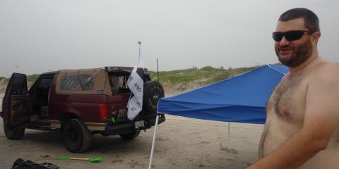 1996 Ford Bronco - A maroon Ford Bronco with its doors open is parked on a sandy beach next to a blue canopy. A man wearing sunglasses stands to the right of…