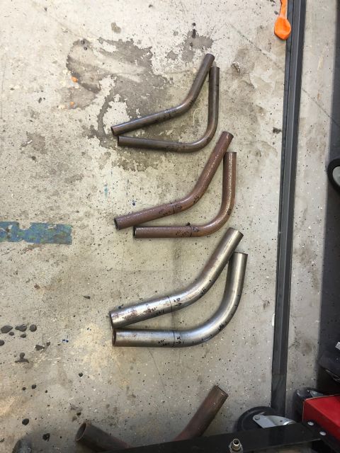 1992 Jeep Wrangler - Several bent metal tubes with markings are laid out on a concrete floor. Some of the tubes are rusty, while others are silver and appear to…