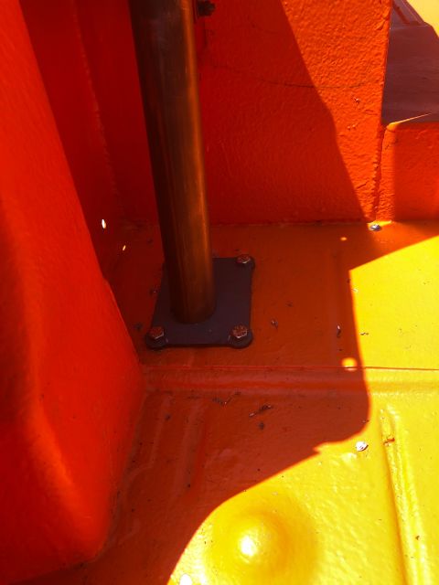 1992 Jeep Wrangler - A close-up view of the interior floor of a vehicle, showing an orange and yellow painted metal surface with a dark metal support pole bolte…