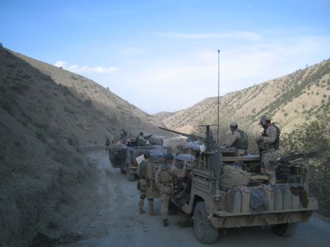 1981 Ford Bronco - A convoy of military vehicles and soldiers travels through a mountainous valley.