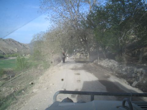 1981 Ford Bronco - A military truck navigates a dirt road in a rural, tree-lined area.