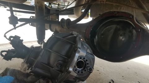 1985 Ford Bronco - The rear differential and a removed differential housing are shown on the underside of a vehicle. The differential housing is black and app…
