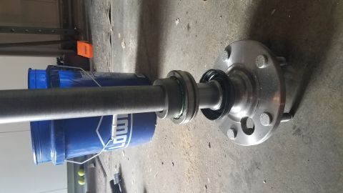 1985 Ford Bronco - A close-up view of a driveshaft assembly with a hub and bolts, supported by blue buckets on a concrete floor.