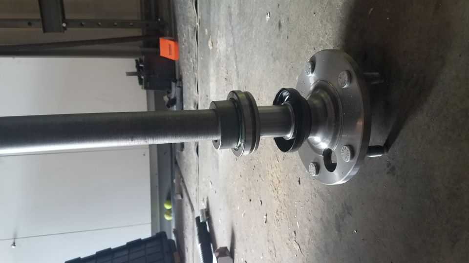 Vehicle axle shaft with bearing and flange on concrete floor