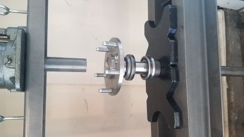 1985 Ford Bronco - A close-up view shows a vehicle hub assembly with five studs mounted on a bearing, positioned between two metal frame components. A hydraul…