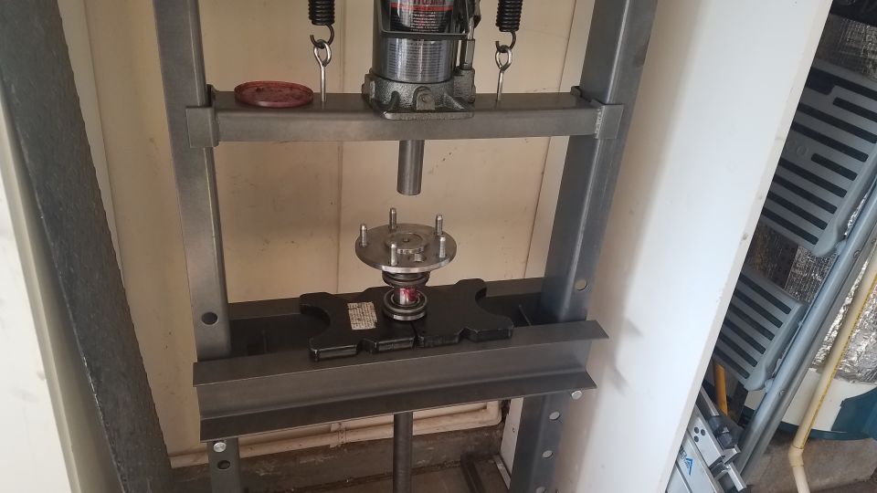 Hydraulic press pressing a wheel bearing onto a wheel hub assembly.