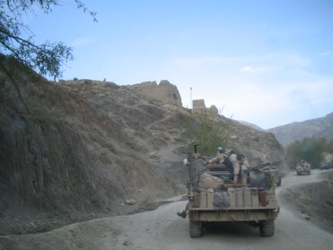 1981 Ford Bronco - Military convoy travels through a , mountainous region with historical ruins visible on the slopes.