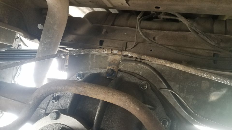 Underside of a vehicle showing rear differential, leaf springs, and brake lines.