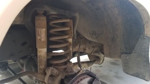 1985 Ford Bronco - This is a close-up view of the front suspension of a 1985 Ford Bronco, showing the shock absorber, coil spring, and brake rotor. The compon…