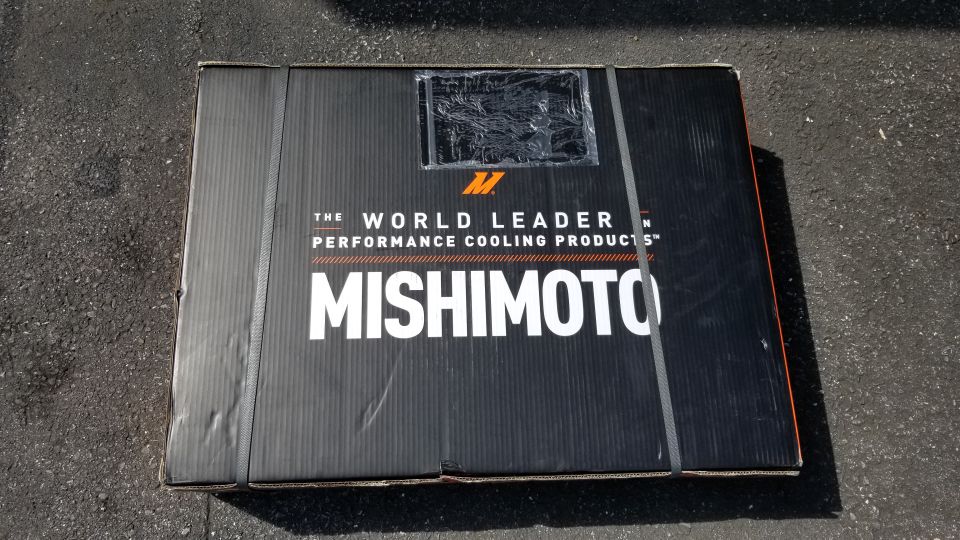 Black Mishimoto box with logo and text on asphalt.