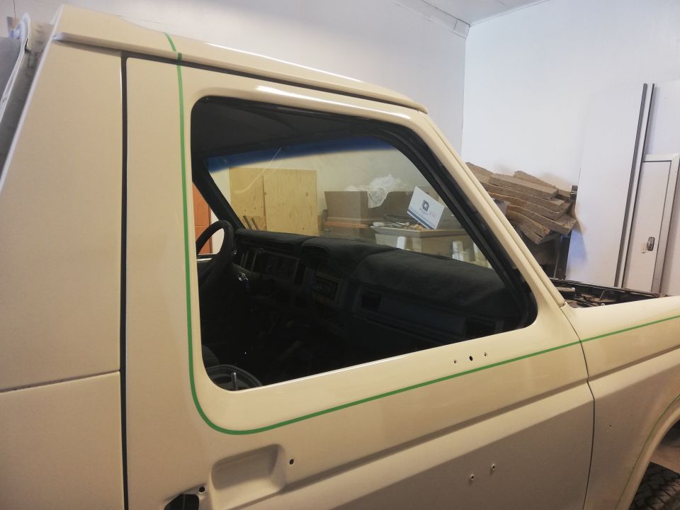 Cream-colored vehicle with green trim, showing the driver's side door and interior.