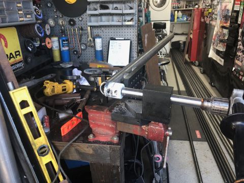 1992 Jeep Wrangler - A metal tube is being held in a vise and worked on with a drill and chuck attachment. The workbench is cluttered with tools and supplies.