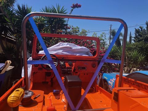 1992 Jeep Wrangler - The interior of an orange Jeep Wrangler is shown with a custom roll cage being installed, secured with blue tape. The dashboard and steerin…