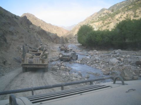 1981 Ford Bronco - A convoy of military vehicles navigates a challenging terrain in a mountainous region.