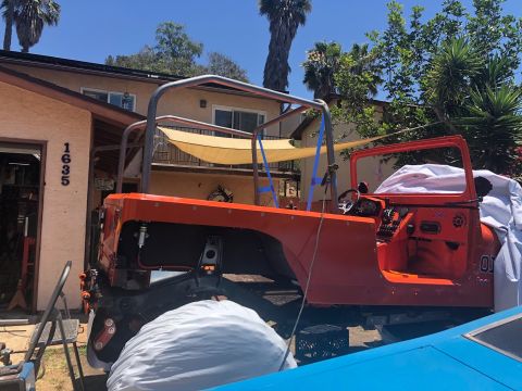 1992 Jeep Wrangler - An orange Jeep Wrangler is parked in a driveway next to a house. The vehicle is partially disassembled with a roll cage installed and a whi…