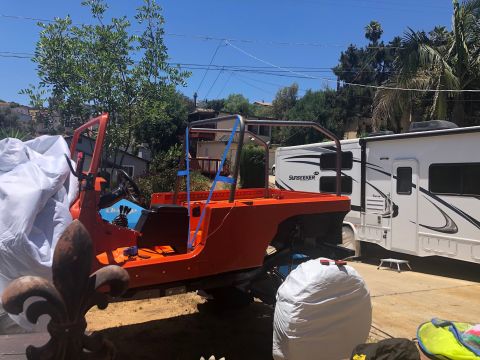 1992 Jeep Wrangler - An orange Jeep tub with a roll cage is parked outdoors next to a white RV. The Jeep appears to be undergoing a restoration or modification.