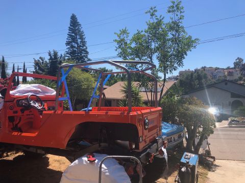 1992 Jeep Wrangler - An orange Jeep Wrangler is undergoing modifications, featuring a newly installed roll cage. The vehicle is parked outdoors in a residential…