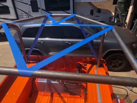 1992 Jeep Wrangler - The orange bed of a Jeep Wrangler is visible, featuring a custom roll cage secured with blue tape. A dark grey Jeep Grand Cherokee is parke…