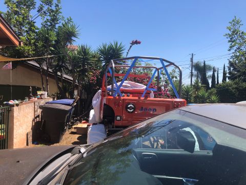 1992 Jeep Wrangler - The rear section of an orange Jeep Wrangler is visible, featuring a custom roll cage wrapped in blue tape. The vehicle is parked outdoors i…