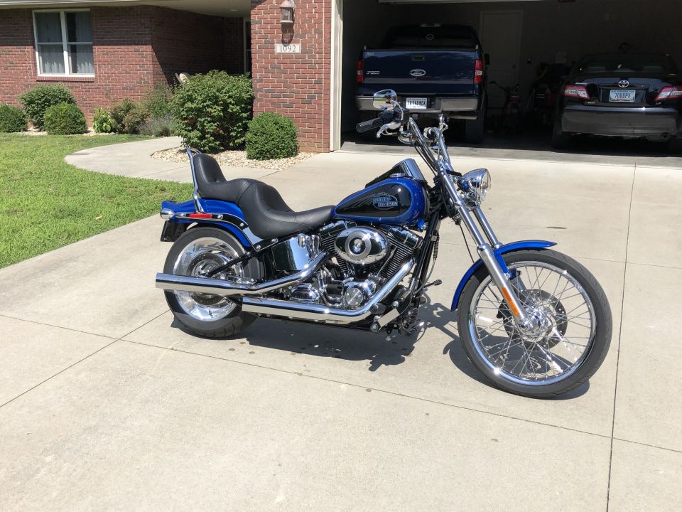Blue and black Harley-Davidson Softail motorcycle with chrome details parked on a driveway.