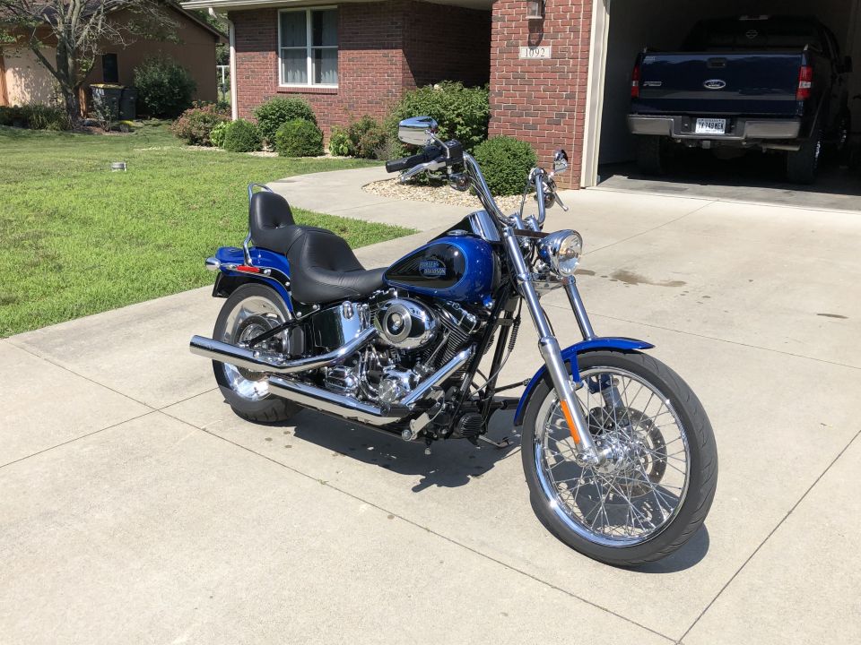 Blue Harley-Davidson Softail motorcycle parked on a concrete driveway.