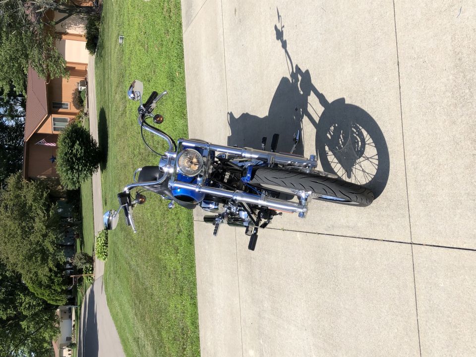 Blue Harley-Davidson motorcycle parked on a concrete driveway with a shadow.