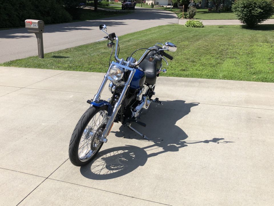 Blue Harley-Davidson Softail motorcycle parked on a concrete driveway.