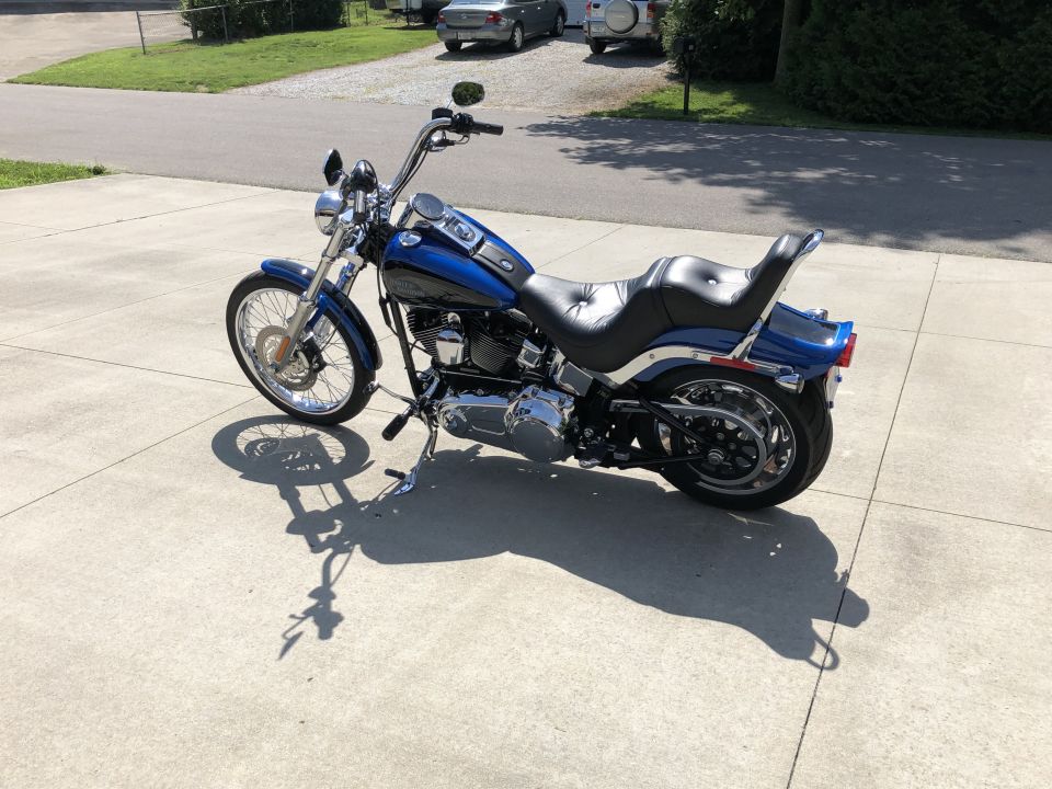 Blue Harley-Davidson Softail motorcycle with chrome accents parked on a concrete driveway.