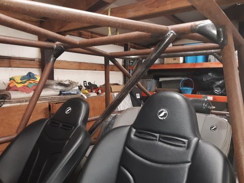 1985 Toyota Hilux - The interior of a vehicle shows a custom roll cage and two racing seats with the 'Corbeau Seats' logo.