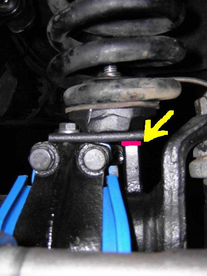 1981 Ford Bronco - Underbody close-up of a coil spring seated on its perch above an axle-end bracket, with a yellow arrow and pink marker line drawn on the ph…