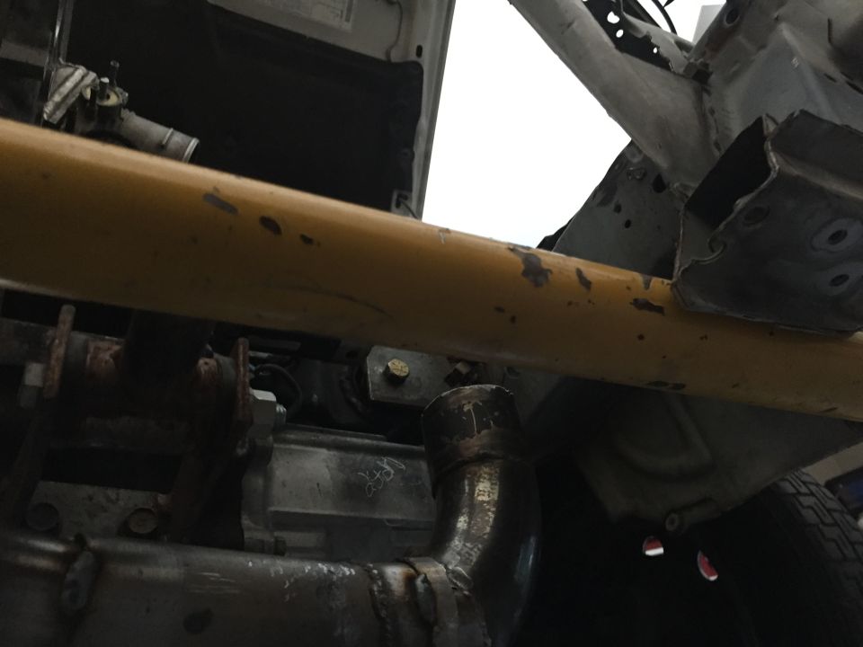 Undercarriage view of a vehicle with a yellow bar and exhaust pipe. Supermotors.net logo visible