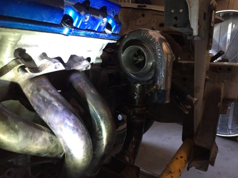 1993 Mercury Tracer - Close-up of a turbocharger being installed onto an exhaust manifold, likely for an engine modification.