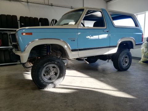 1996 Ford Bronco - This two-tone Ford Bronco features a lifted suspension and large off-road tires, suggesting it's prepared for terrain.