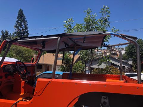 1992 Jeep Wrangler - The interior of an orange Jeep Wrangler is shown with a custom roll cage and soft top overhead.