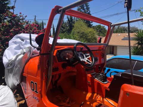 1992 Jeep Wrangler - Custom orange Jeep interior features a roll cage, aftermarket steering wheel, and racing-style gauges.