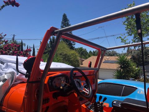 1992 Jeep Wrangler - Interior view of an orange Jeep with a custom roll cage, a blue car is parked behind it.