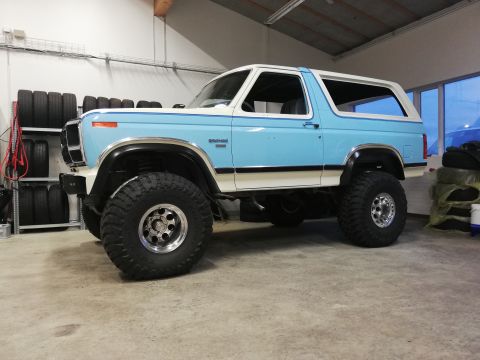 1996 Ford Bronco - This lifted Ford Bronco is parked inside a garage with tires stacked on shelves in the background.