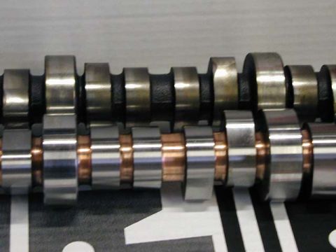1979 Ford Bronco - Close-up view of two engine camshafts, highlighting their distinct lobe and spacer designs.