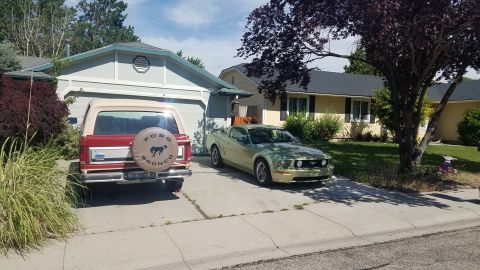 1985 Ford Bronco - A red 1985 Ford Bronco is parked in a driveway next to a modern Ford Mustang.