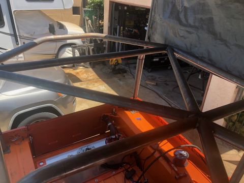 1992 Jeep Wrangler - A custom roll cage is being fabricated and welded onto an orange vehicle, possibly a Jeep, in an outdoor garage setting. The roll cage stru…