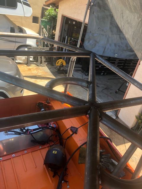1992 Jeep Wrangler - A custom roll cage is being welded into the interior of an orange vehicle. The vehicle appears to be a Jeep Wrangler, with parts of the ext…