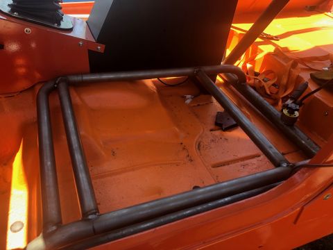 1992 Jeep Wrangler - The interior of an orange Jeep Wrangler shows a custom-fabricated metal roll cage installed over the floor pan. The roll cage is constructe…